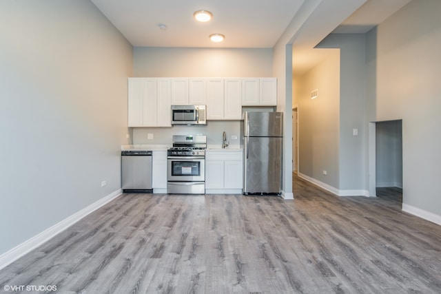 kitchen featuring appliances with stainless steel finishes, light hardwood / wood-style flooring, and white cabinetry