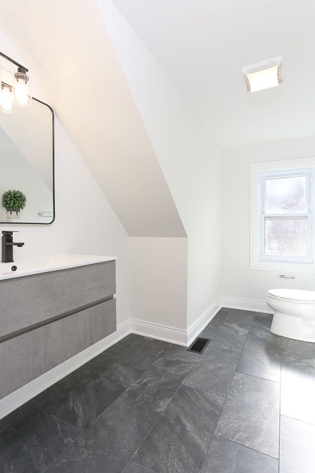 bathroom with vanity, toilet, and vaulted ceiling