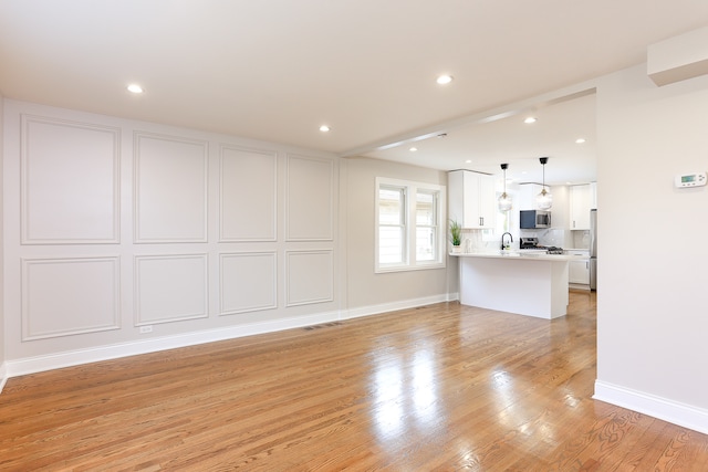 unfurnished living room featuring light wood-type flooring and sink