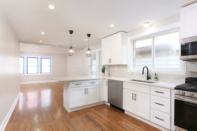 kitchen featuring white cabinets, kitchen peninsula, sink, and appliances with stainless steel finishes