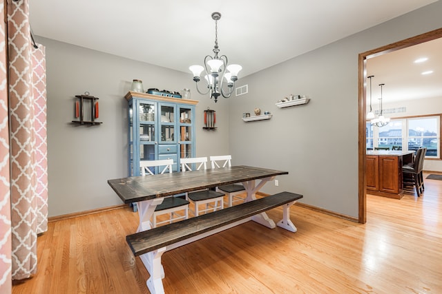 dining area with a notable chandelier and light hardwood / wood-style flooring