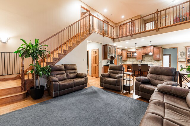 living room with light hardwood / wood-style floors and a towering ceiling