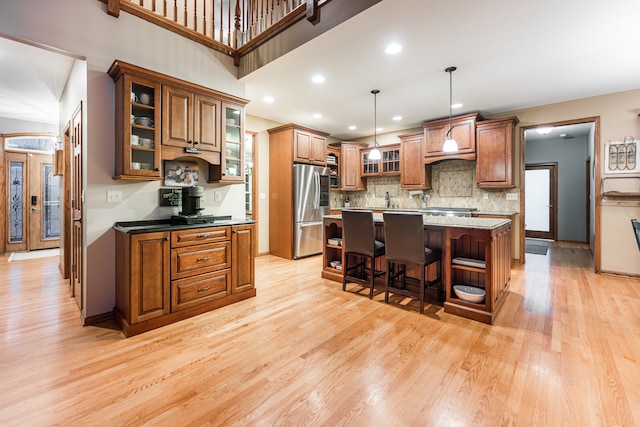 kitchen with stainless steel refrigerator, light hardwood / wood-style floors, decorative light fixtures, a kitchen bar, and a kitchen island