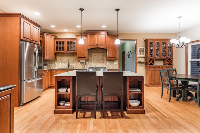 kitchen with light stone countertops, appliances with stainless steel finishes, a center island with sink, and a chandelier