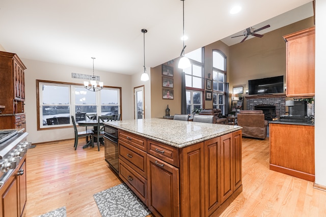 kitchen featuring light stone countertops, decorative light fixtures, a fireplace, light hardwood / wood-style floors, and a kitchen island