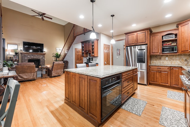 kitchen with a center island, light wood-type flooring, a fireplace, and appliances with stainless steel finishes