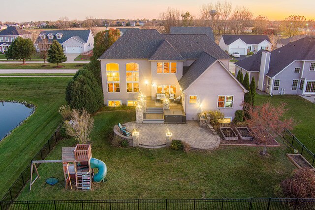 back house at dusk with an outdoor living space, a yard, a playground, and a patio area