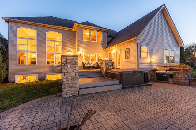 back house at dusk featuring a patio and a hot tub