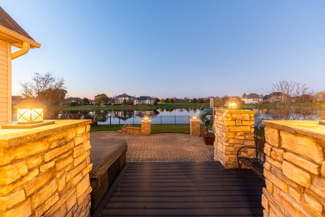 deck at dusk featuring a water view