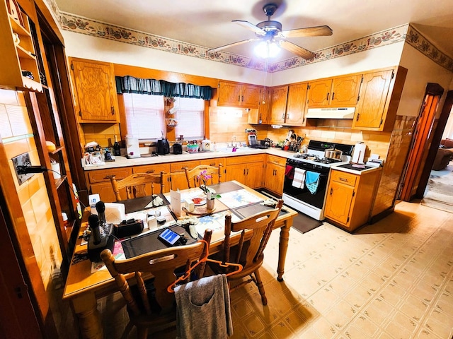 kitchen with decorative backsplash, gas range gas stove, sink, and ceiling fan