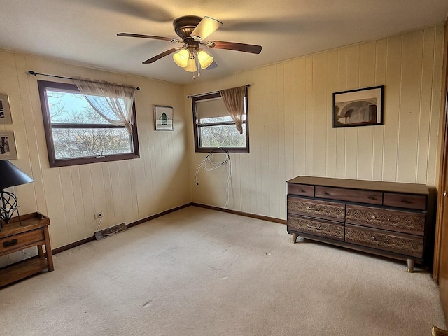 carpeted bedroom featuring multiple windows, ceiling fan, and wooden walls