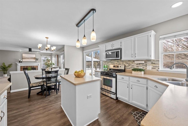 kitchen with sink, decorative light fixtures, white cabinets, and appliances with stainless steel finishes