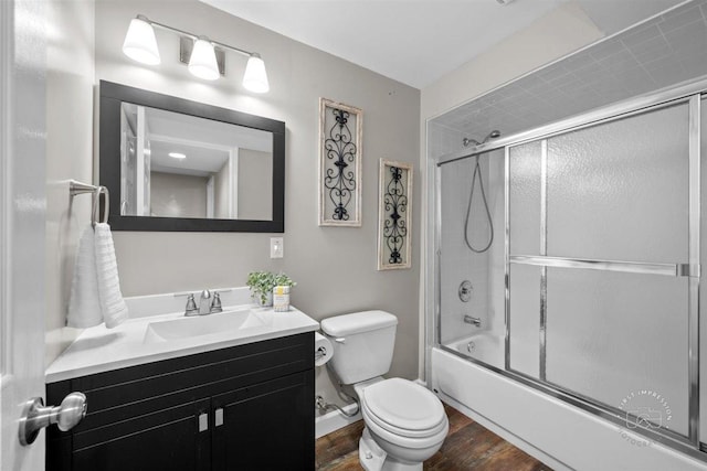 full bathroom featuring wood-type flooring, toilet, combined bath / shower with glass door, and vanity