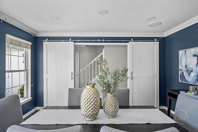 interior space with ornamental molding, a barn door, and wood-type flooring