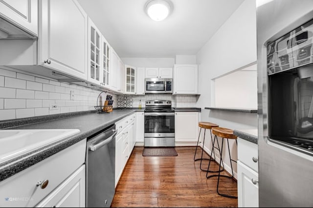 kitchen with white cabinets, decorative backsplash, dark wood-type flooring, and appliances with stainless steel finishes