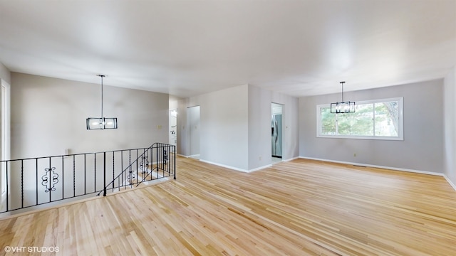 unfurnished room featuring light hardwood / wood-style floors and an inviting chandelier