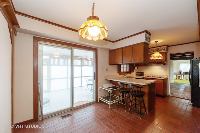 kitchen with kitchen peninsula, pendant lighting, a healthy amount of sunlight, and a breakfast bar area