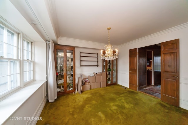 unfurnished dining area featuring a chandelier, dark carpet, and ornamental molding