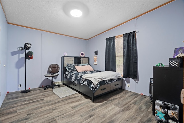 bedroom with hardwood / wood-style flooring, crown molding, and a textured ceiling