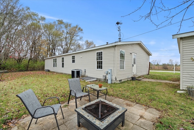 back of property featuring a fire pit, central AC unit, a yard, and a patio