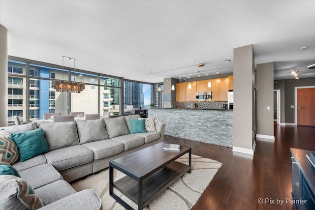 living room with a chandelier, dark hardwood / wood-style flooring, track lighting, and floor to ceiling windows