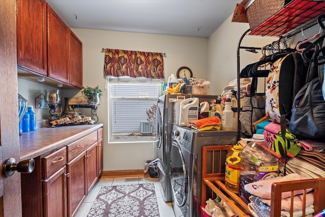 clothes washing area with cabinets, light tile patterned floors, and washing machine and clothes dryer