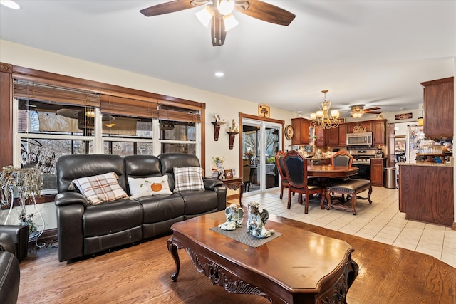 tiled living room featuring ceiling fan with notable chandelier