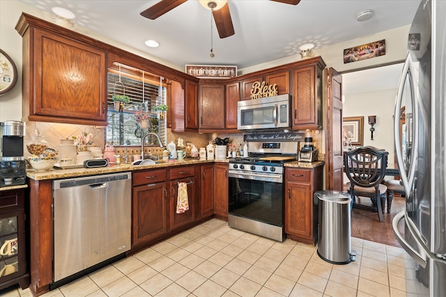 kitchen featuring decorative backsplash, appliances with stainless steel finishes, light wood-type flooring, light stone counters, and sink