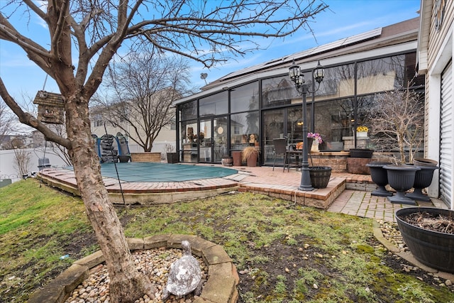 view of yard with a sunroom, a patio, and a covered pool