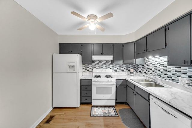 kitchen with gray cabinets, sink, decorative backsplash, white appliances, and light hardwood / wood-style flooring