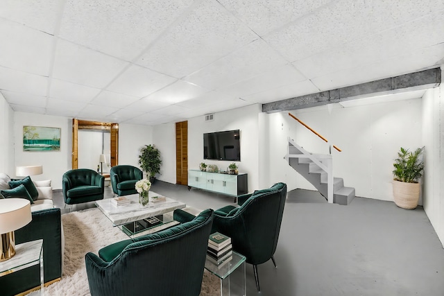 living room featuring concrete flooring and a drop ceiling