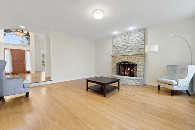 living room with light wood-type flooring, a fireplace, and baseboards