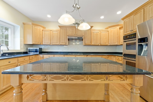 kitchen featuring appliances with stainless steel finishes, decorative light fixtures, a kitchen island, and a kitchen breakfast bar