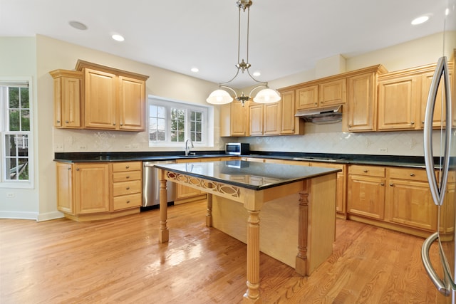 kitchen featuring a healthy amount of sunlight, a kitchen island, stainless steel appliances, and light hardwood / wood-style flooring