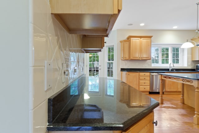 kitchen with dark stone counters, light brown cabinetry, a wealth of natural light, and light hardwood / wood-style flooring