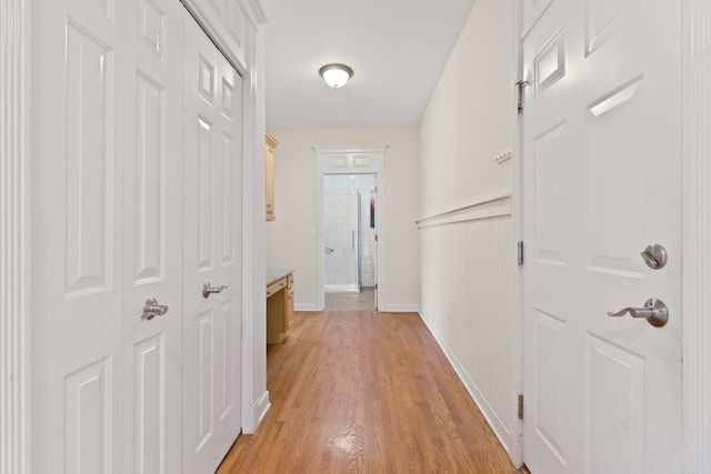 hallway featuring light wood-style flooring and baseboards