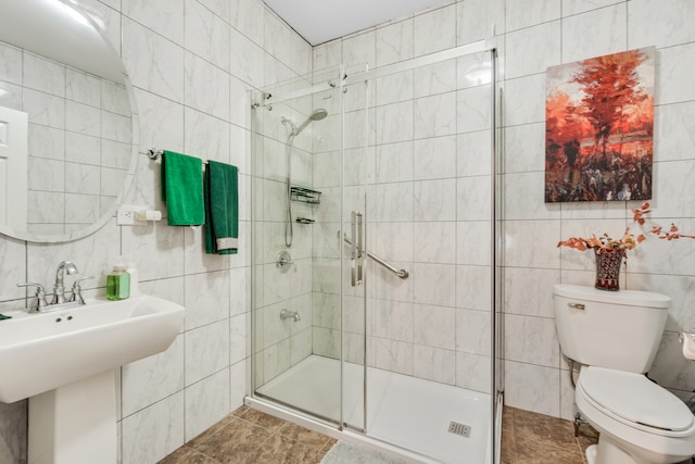 full bath with toilet, a shower stall, a sink, and tile walls