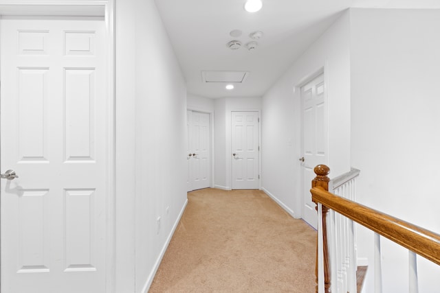 hallway with attic access, light carpet, an upstairs landing, and baseboards