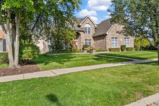 traditional-style house with a shingled roof, a front lawn, and brick siding