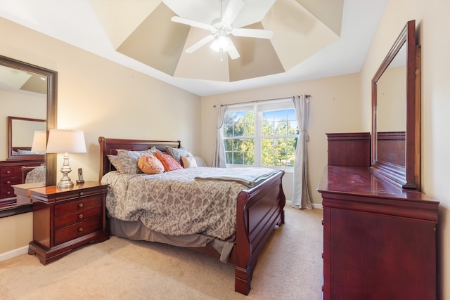 bedroom with light carpet, a raised ceiling, and baseboards