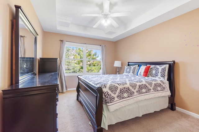 bedroom featuring a raised ceiling, ceiling fan, and light colored carpet