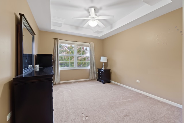 interior space featuring light carpet, a raised ceiling, and ceiling fan