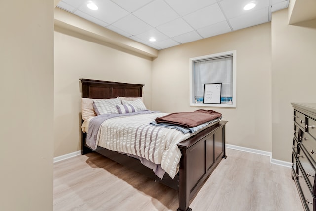 bedroom with a paneled ceiling and light hardwood / wood-style floors