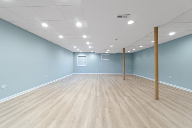 finished below grade area with recessed lighting, a paneled ceiling, visible vents, light wood-style flooring, and baseboards