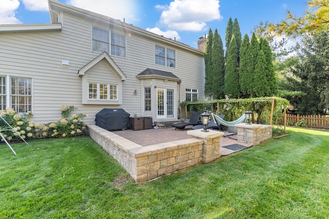 rear view of house with a chimney, a lawn, a patio area, and fence