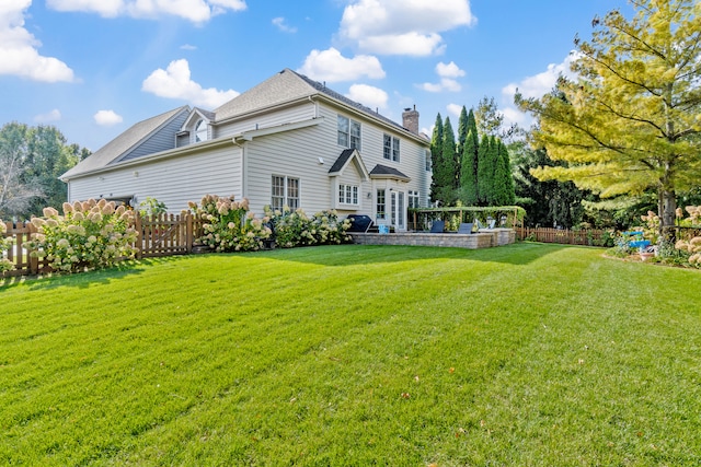 rear view of property featuring fence, a chimney, and a lawn