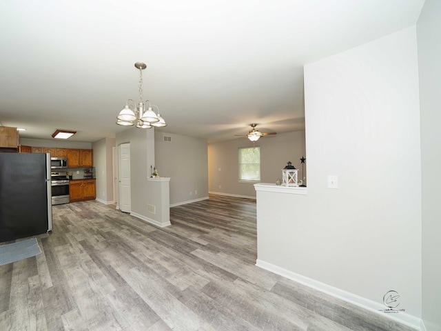 kitchen featuring appliances with stainless steel finishes, ceiling fan with notable chandelier, hanging light fixtures, and light wood-type flooring