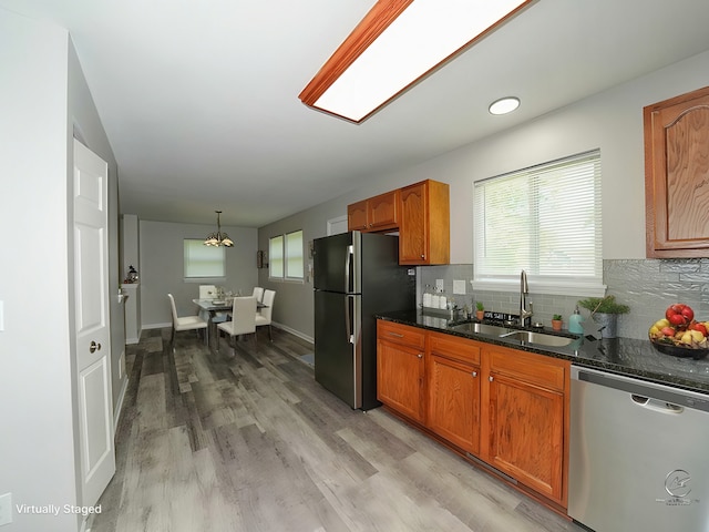 kitchen with sink, hanging light fixtures, stainless steel appliances, light hardwood / wood-style floors, and backsplash