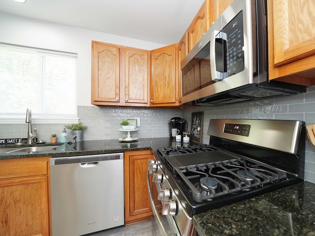 kitchen featuring dark stone countertops, sink, tasteful backsplash, and appliances with stainless steel finishes