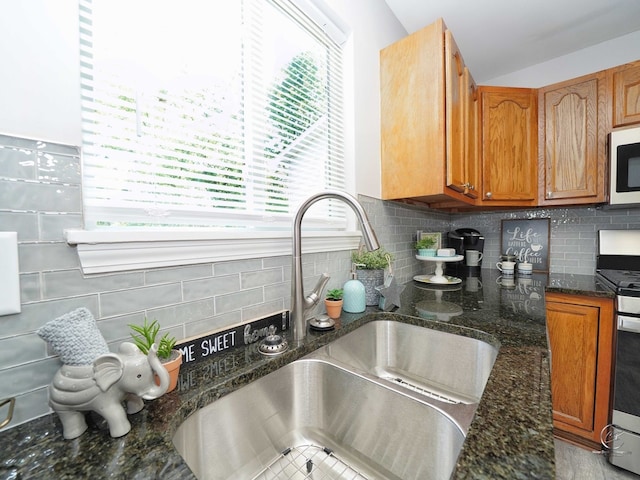 kitchen with vaulted ceiling, gas stove, decorative backsplash, and dark stone countertops